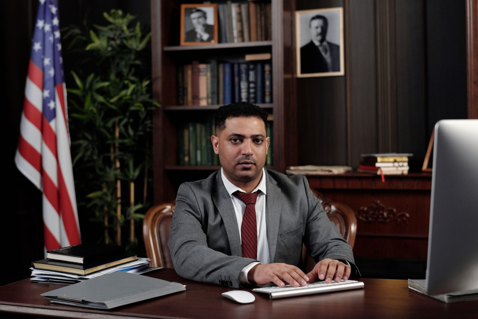 Corporate professional sitting at desk with American flag in office.